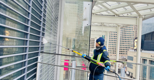 Pressure washing the exterior of a building, with water spray cleaning the facade to remove dirt and grime.