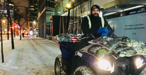 Snow removal using an ATV on the sidewalk in front of a commercial building, clearing snow for safe passage